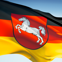 Eine wehende Deutschlandflagge mit dem niedersächsischen Wappen darauf.