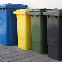 Eine blaue, gelbe, grüne und graue Mülltonne ist abgebildet.